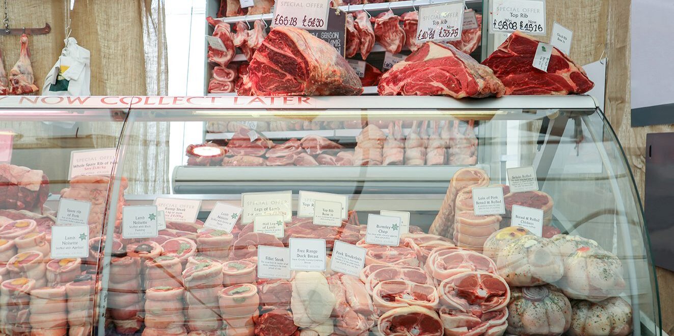 Variety of raw meat in chiller display at Butcher shop.